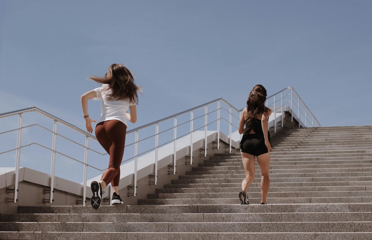 2 Women Walking on Gray Concrete Bridge