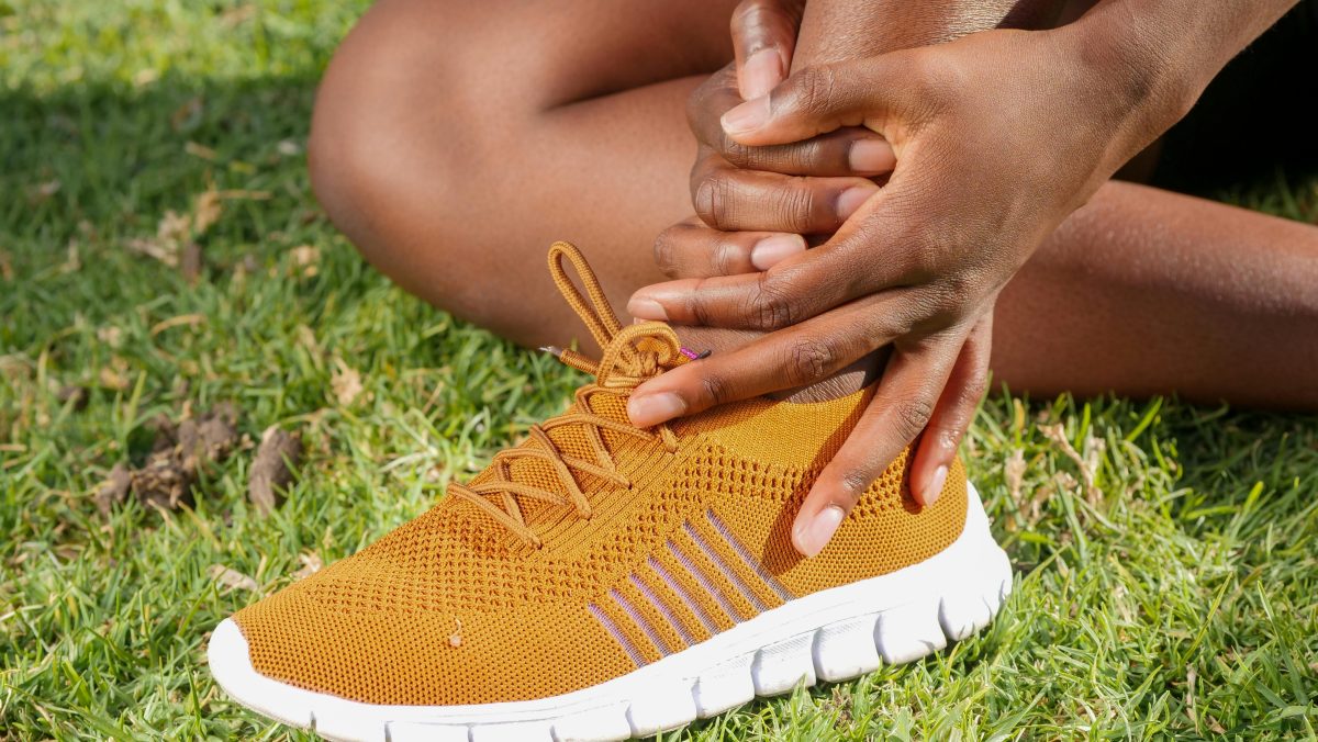 girl holding her bare foot in pain