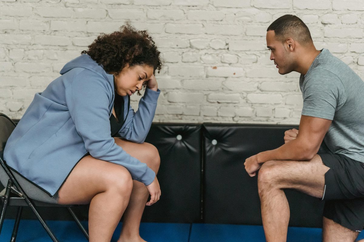 Tired black woman with trainer in gym