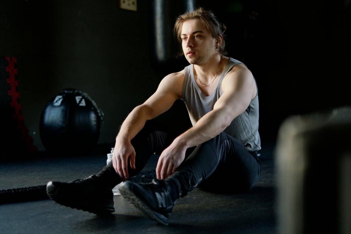 Sweaty tired muscular sportsman resting after workout in gym